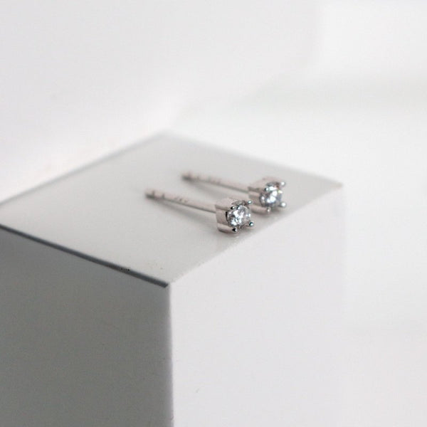 Silver stud earrings on a white surface with a light gray background