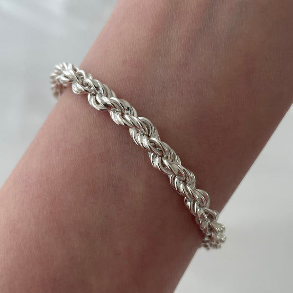 Silver braided bracelet on a wrist against a white background