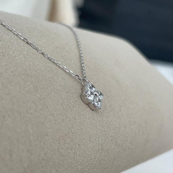 Silver necklace with a floral pendant on a neutral background