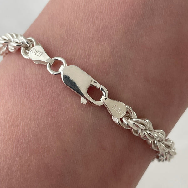 Silver braided bracelet on a wrist with a close-up of the clasp.