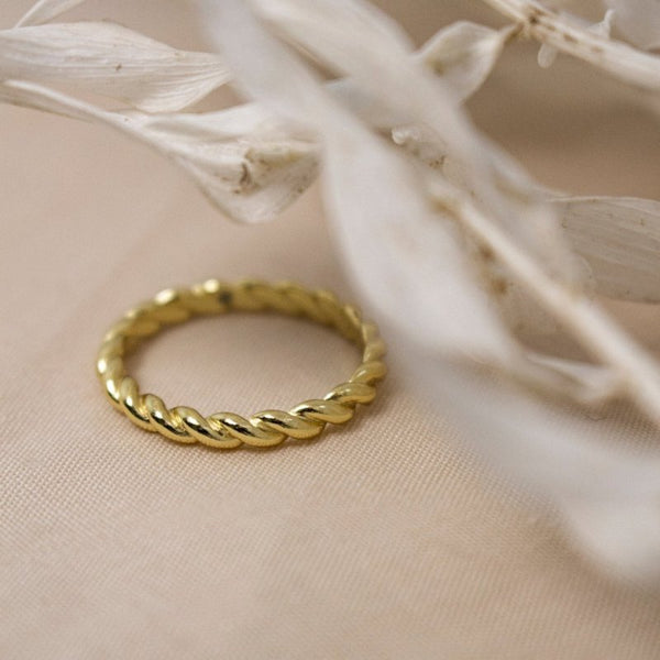 Gold ring on a beige fabric background with dried white flowers