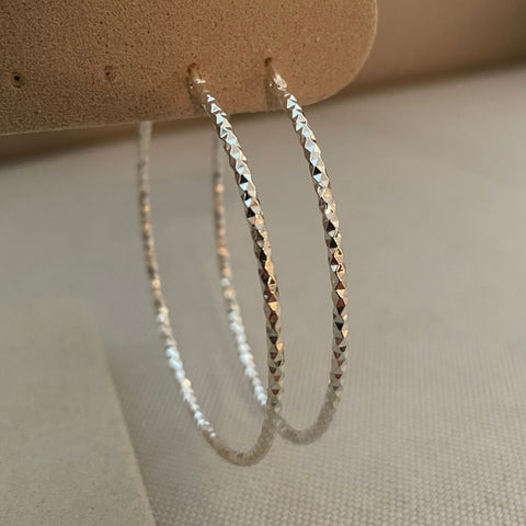 Silver bracelet on a beige stand with a neutral background