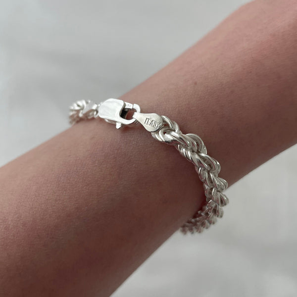 Silver bracelet on a wrist against a white background