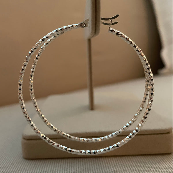 Silver hoop earring on a beige surface