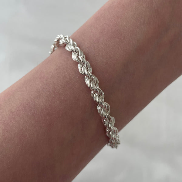 Silver braided bracelet on a wrist against a white background