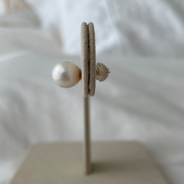 Pearl earring on a white stand with a blurred background