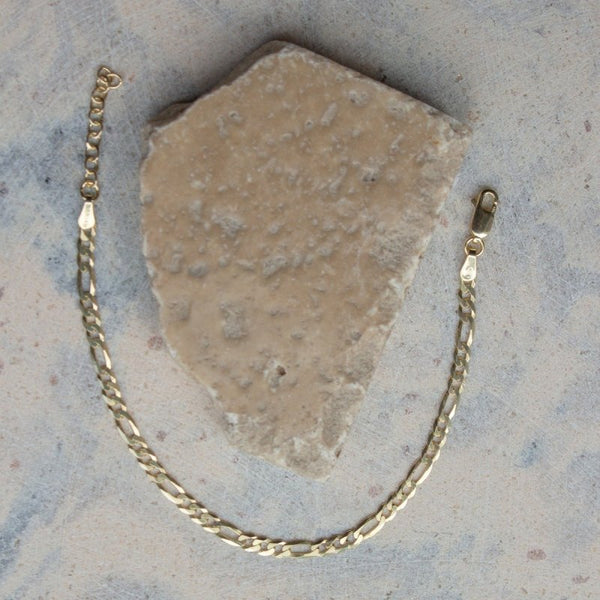Gold chain necklace on a textured stone surface