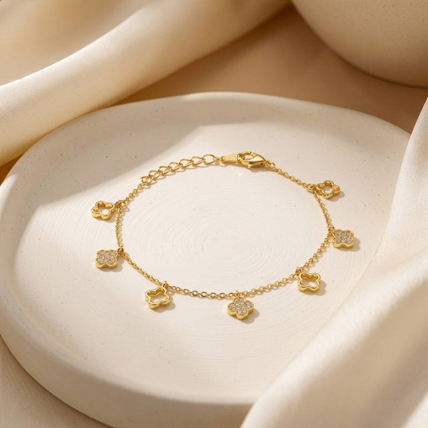 Gold bracelet with floral charms on a beige stone surface