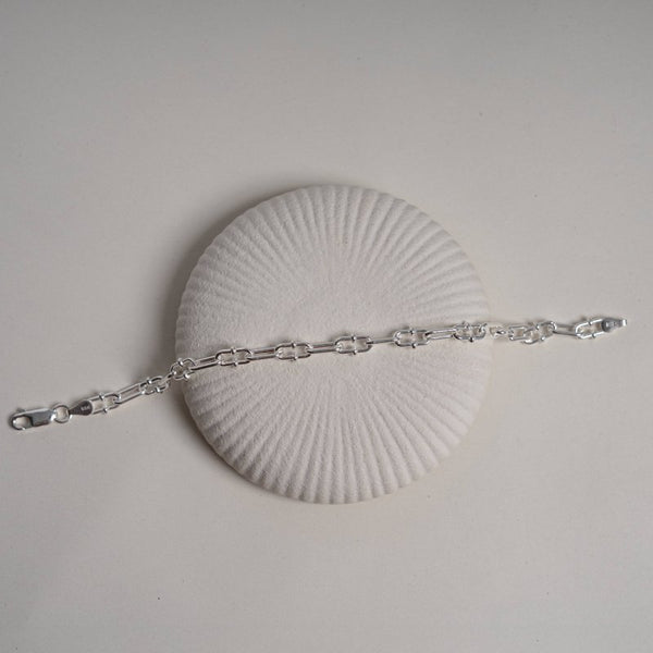 Silver bracelet on a white shell against a light gray background