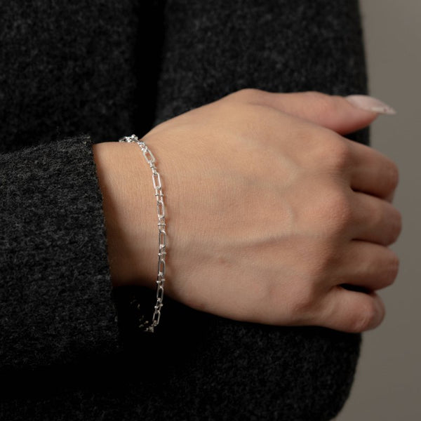 Hand wearing a silver bracelet with a blurred background