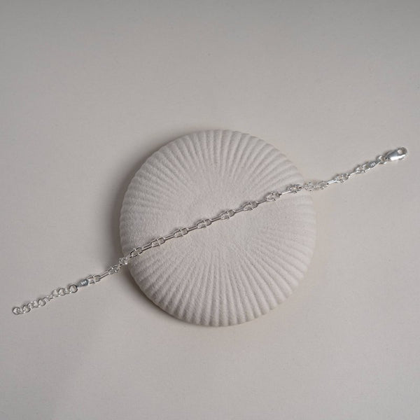 Silver bracelet on a white shell with a light gray background
