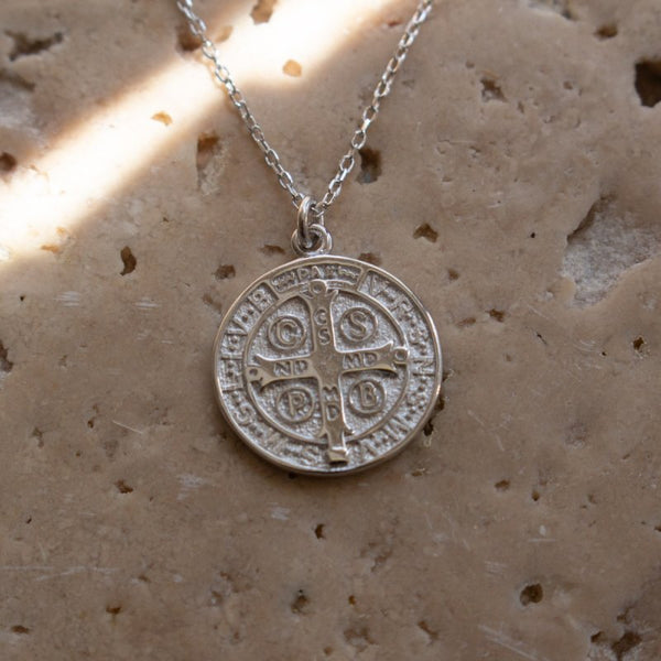 Silver necklace with a round pendant on a textured beige surface