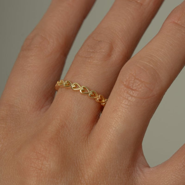 Gold ring on a person's finger against a neutral background