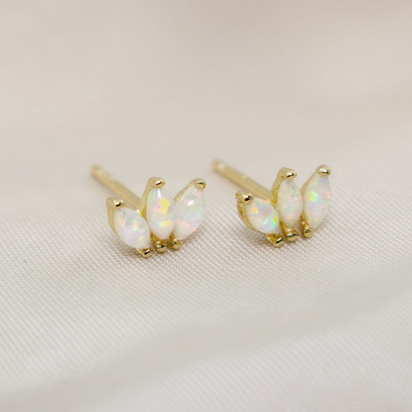 Opal stud earrings with gold posts on a light fabric background